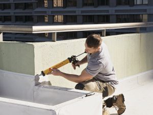 Man waterproofing a roof's wall